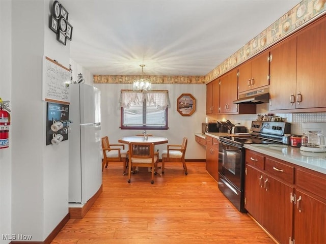 kitchen with backsplash, hanging light fixtures, electric range, light hardwood / wood-style floors, and white fridge