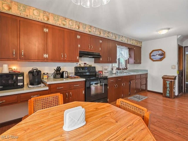 kitchen with light hardwood / wood-style floors, sink, decorative backsplash, and black appliances