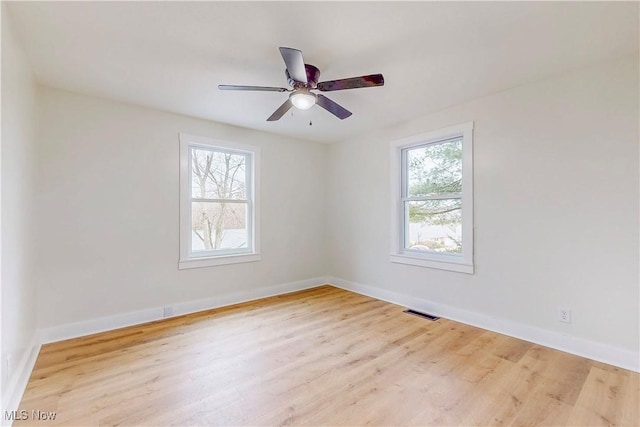 empty room with light hardwood / wood-style flooring, a wealth of natural light, and ceiling fan