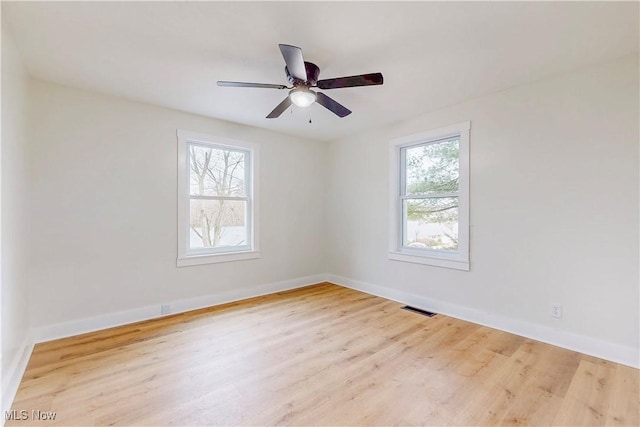 empty room with plenty of natural light, ceiling fan, and light wood-type flooring