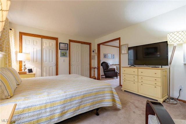 bedroom with multiple closets and light carpet