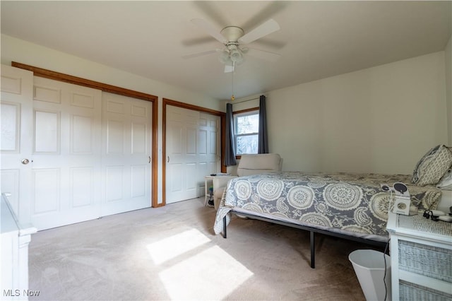 carpeted bedroom with ceiling fan and two closets