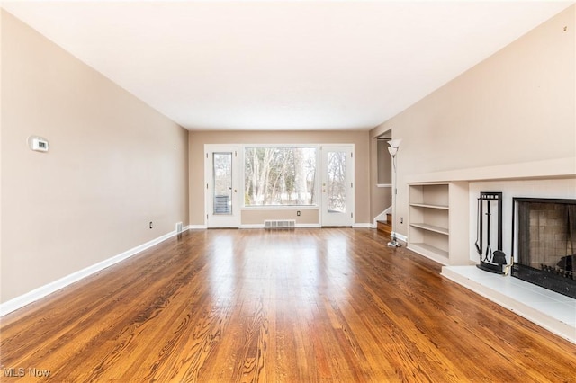 unfurnished living room featuring hardwood / wood-style floors and built in features