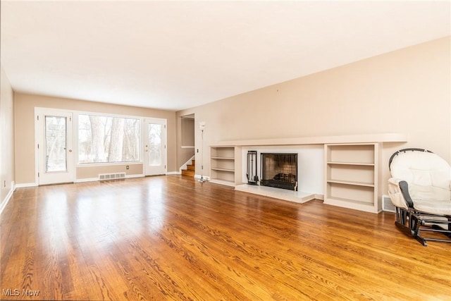 unfurnished living room featuring hardwood / wood-style floors and built in features