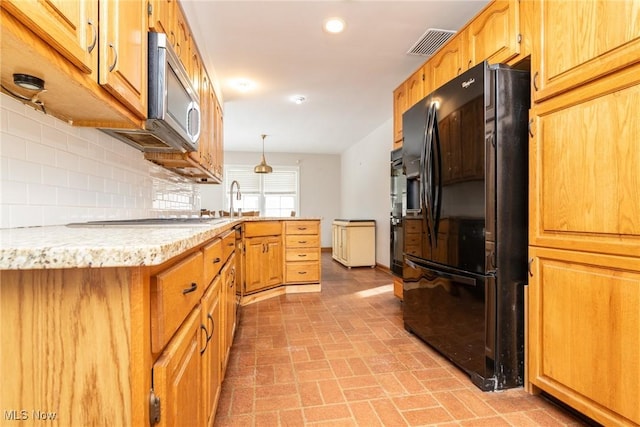 kitchen featuring backsplash, sink, hanging light fixtures, and black appliances