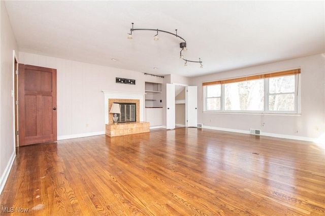 unfurnished living room with hardwood / wood-style flooring, a fireplace, and built in shelves