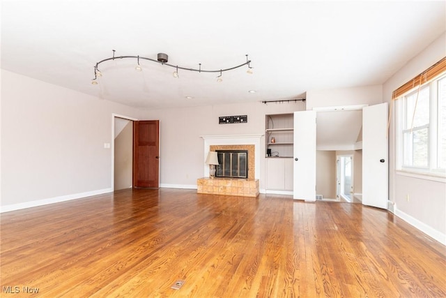 unfurnished living room featuring hardwood / wood-style flooring and track lighting