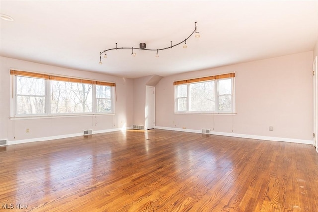 empty room with track lighting and wood-type flooring