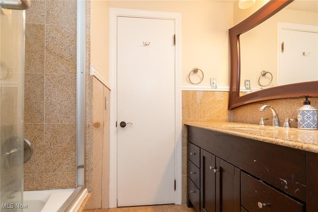 bathroom featuring tiled shower, vanity, decorative backsplash, and tile walls