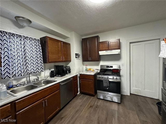 kitchen featuring sink, dark brown cabinets, a textured ceiling, appliances with stainless steel finishes, and dark hardwood / wood-style flooring