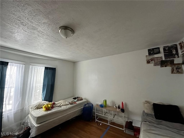 bedroom with a textured ceiling and dark hardwood / wood-style flooring