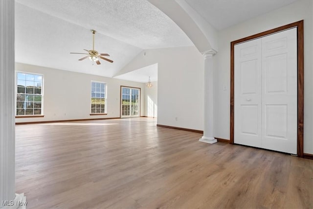 unfurnished living room with decorative columns, lofted ceiling, ceiling fan, a textured ceiling, and light wood-type flooring