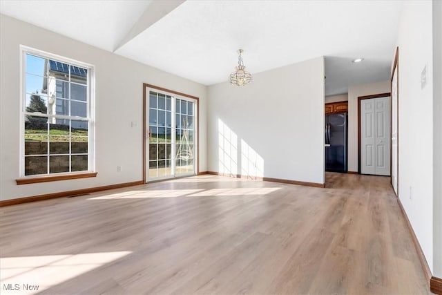 unfurnished room featuring an inviting chandelier and light wood-type flooring