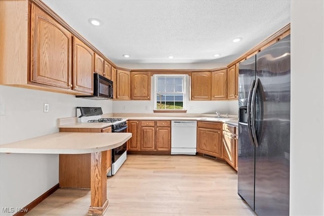 kitchen with sink, white appliances, light hardwood / wood-style floors, kitchen peninsula, and a textured ceiling