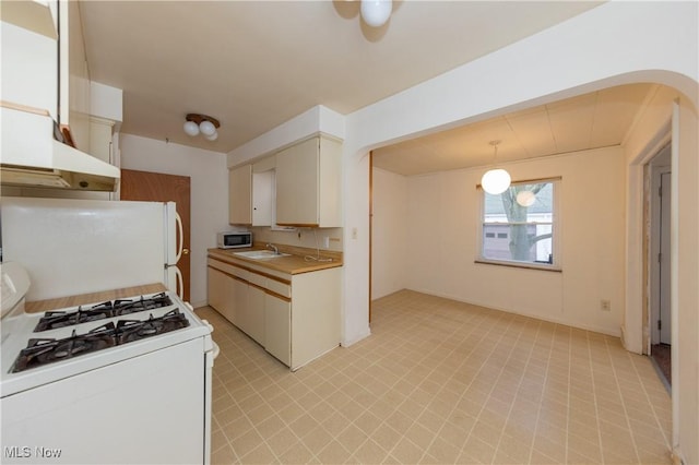 kitchen with pendant lighting, sink, white appliances, and white cabinetry