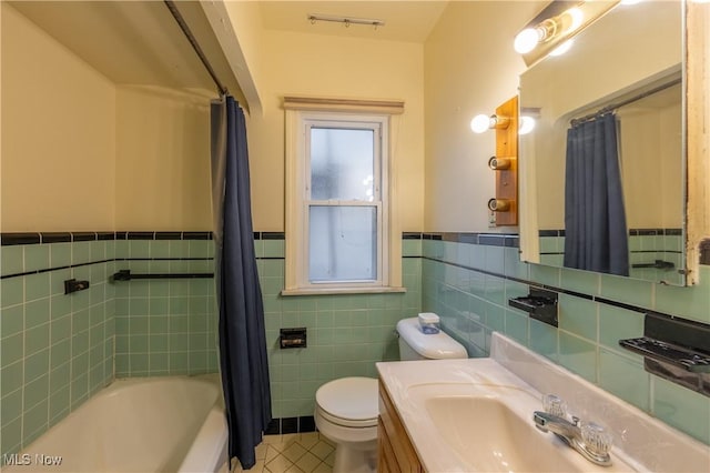 full bathroom with toilet, tile walls, vanity, shower / bath combo with shower curtain, and tile patterned flooring