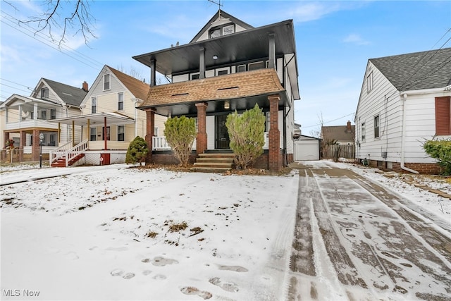 snow covered property with a garage, a balcony, and a porch