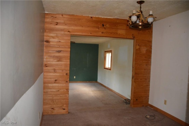 spare room with wooden walls and a chandelier