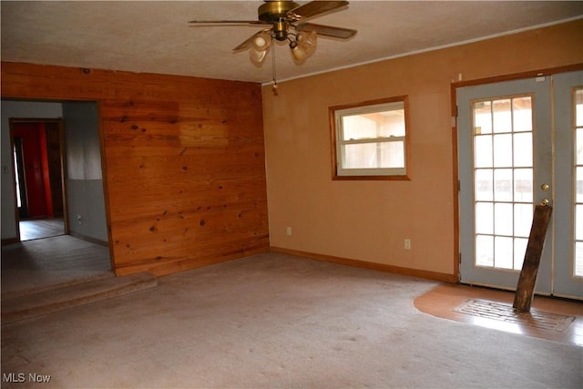 empty room with carpet flooring, ceiling fan, and wood walls