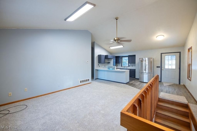 kitchen featuring stainless steel refrigerator, lofted ceiling, kitchen peninsula, and plenty of natural light