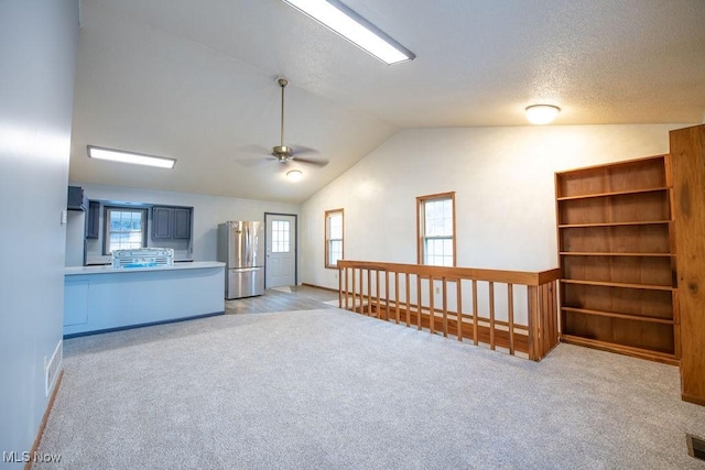 unfurnished room with ceiling fan, lofted ceiling, and light carpet