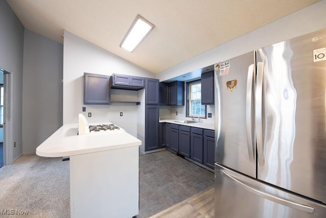 kitchen with lofted ceiling, sink, a breakfast bar area, stainless steel refrigerator, and kitchen peninsula