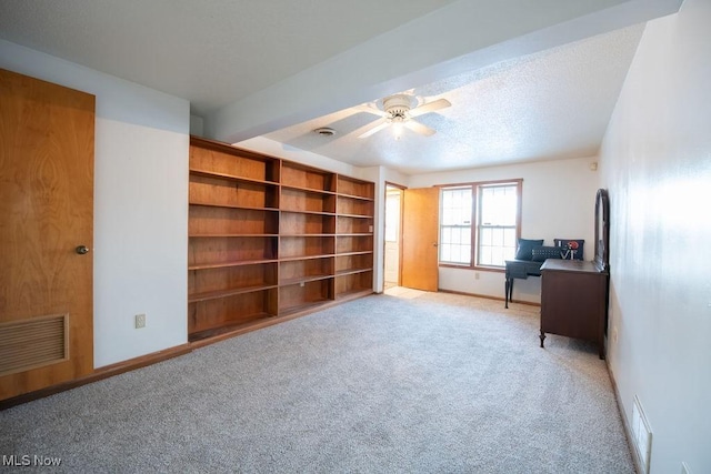 office area featuring beamed ceiling, ceiling fan, light carpet, and a textured ceiling