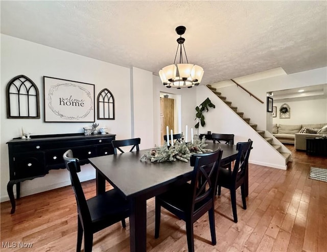 dining area with an inviting chandelier, hardwood / wood-style floors, and a textured ceiling