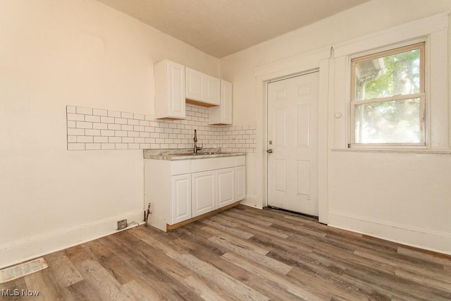 kitchen with white cabinetry, sink, decorative backsplash, and light wood-type flooring