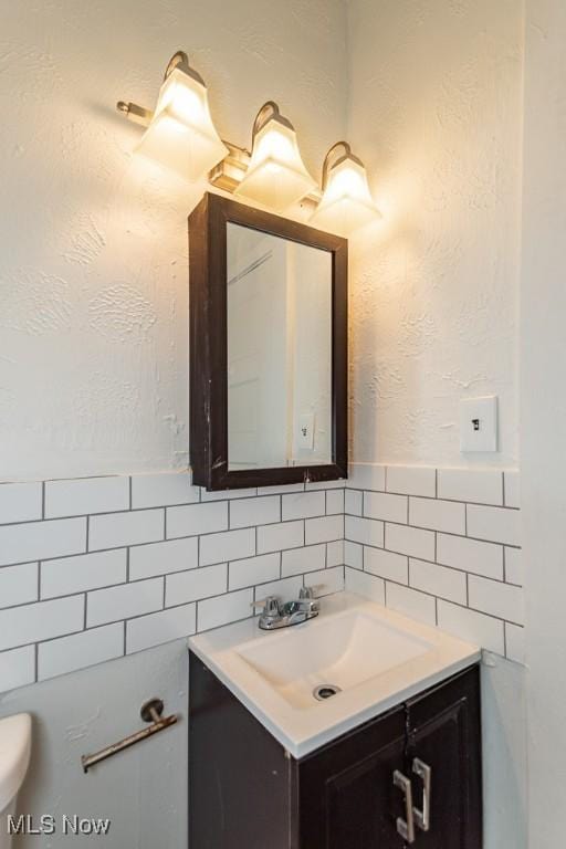 bathroom featuring vanity, tile walls, and toilet