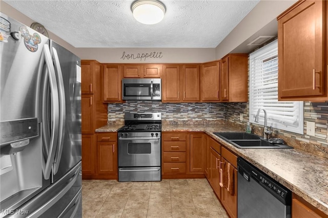 kitchen with sink, backsplash, stainless steel appliances, a textured ceiling, and light tile patterned flooring