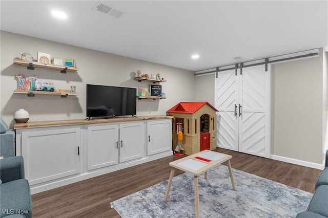 rec room featuring a barn door and dark wood-type flooring