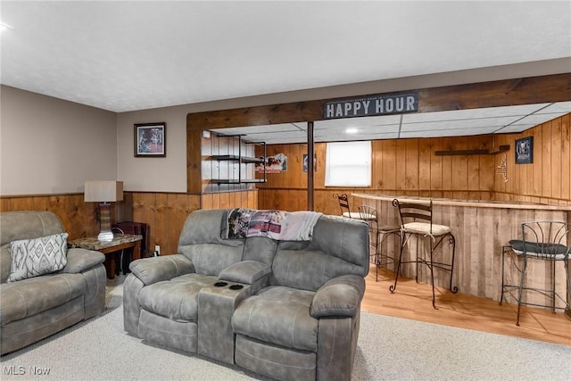 living room featuring bar, wooden walls, and light hardwood / wood-style floors