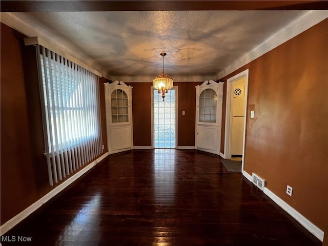 unfurnished dining area with dark hardwood / wood-style flooring, a chandelier, and a textured ceiling