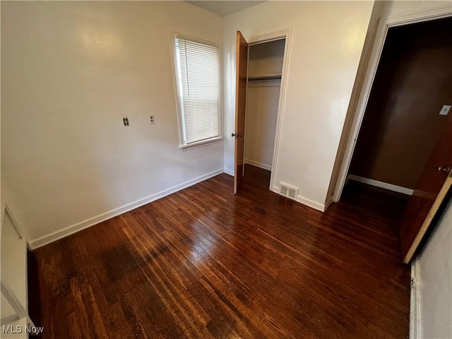 unfurnished bedroom featuring a closet and dark hardwood / wood-style floors