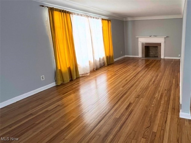 unfurnished living room with crown molding and wood-type flooring