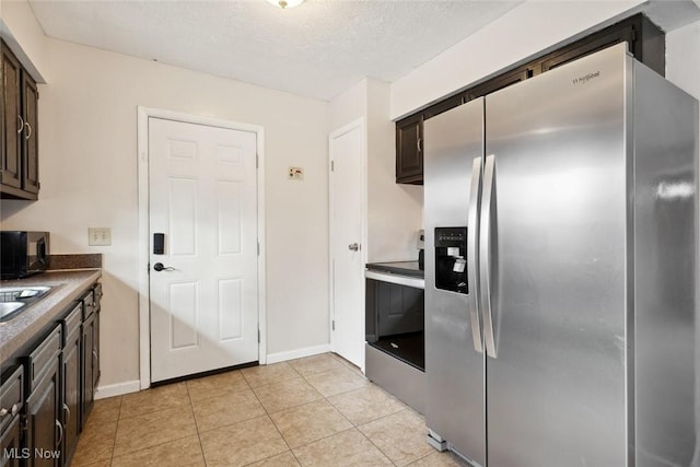 kitchen with stainless steel appliances, dark brown cabinets, light tile patterned floors, and a textured ceiling