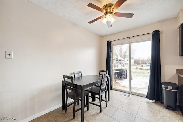 tiled dining room with ceiling fan and a textured ceiling