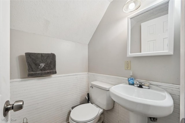 bathroom with vaulted ceiling, sink, a textured ceiling, and toilet