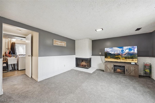 unfurnished living room featuring light colored carpet, a brick fireplace, and a textured ceiling