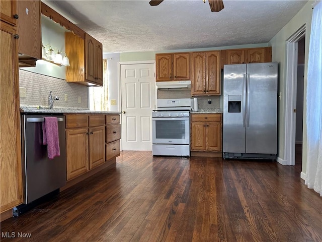 kitchen featuring dark wood-type flooring, tasteful backsplash, appliances with stainless steel finishes, ceiling fan, and light stone countertops