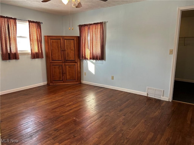 empty room with dark hardwood / wood-style floors, a textured ceiling, and ceiling fan