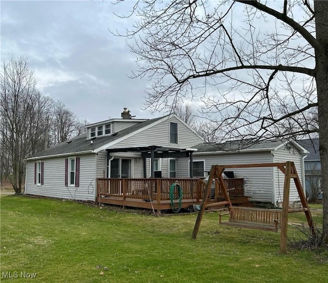 rear view of house featuring a wooden deck and a lawn