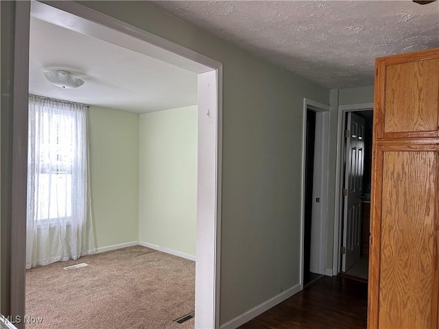 unfurnished room with dark carpet and a textured ceiling