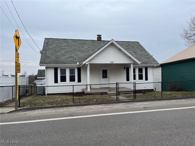 view of front of property with a fenced front yard, a gate, roof with shingles, and a chimney