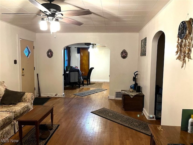 living room with arched walkways, ceiling fan, wood-type flooring, and baseboards