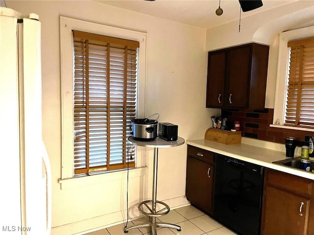 kitchen featuring light tile patterned floors, a sink, black dishwasher, light countertops, and dark brown cabinets