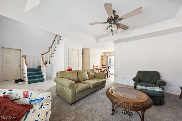 living room with a tray ceiling, ceiling fan with notable chandelier, and carpet