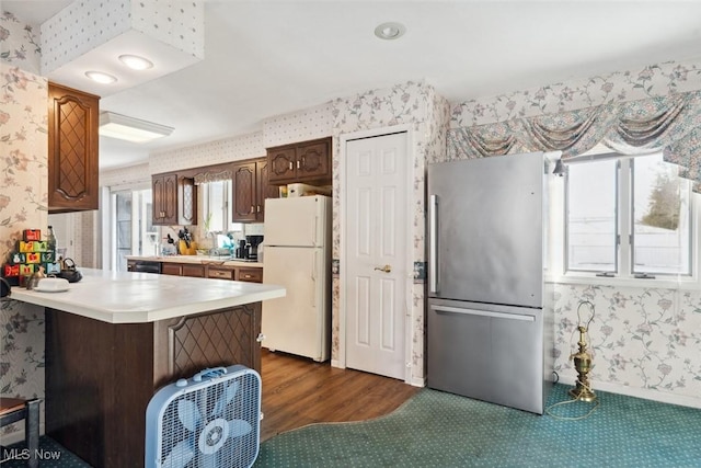 kitchen with a breakfast bar, white refrigerator, stainless steel fridge, kitchen peninsula, and dark hardwood / wood-style floors