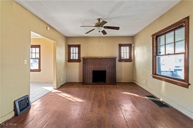 unfurnished living room featuring ceiling fan, a fireplace, and wood-type flooring